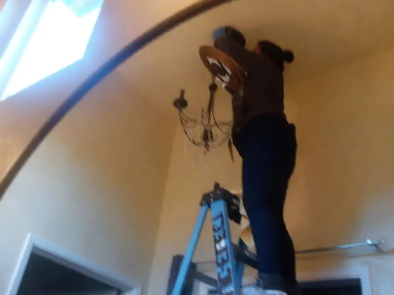Electrician installing a chandelier in a Baker City residence
